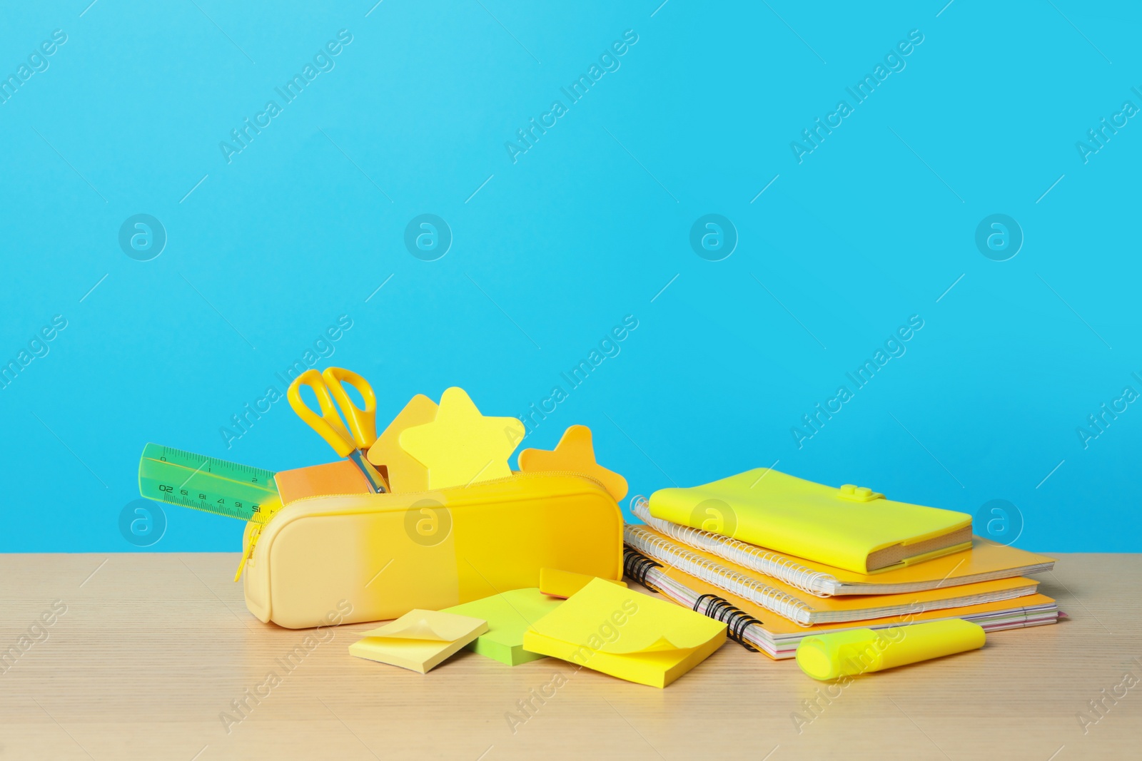 Photo of Composition with different school stationery on wooden table against light blue background, space for text. Back to school