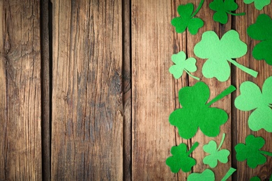 Photo of Decorative clover leaves on wooden background, flat lay with space for text. St. Patrick's Day celebration