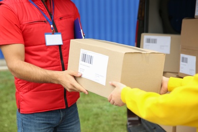 Photo of Courier giving package to customer outdoors, closeup