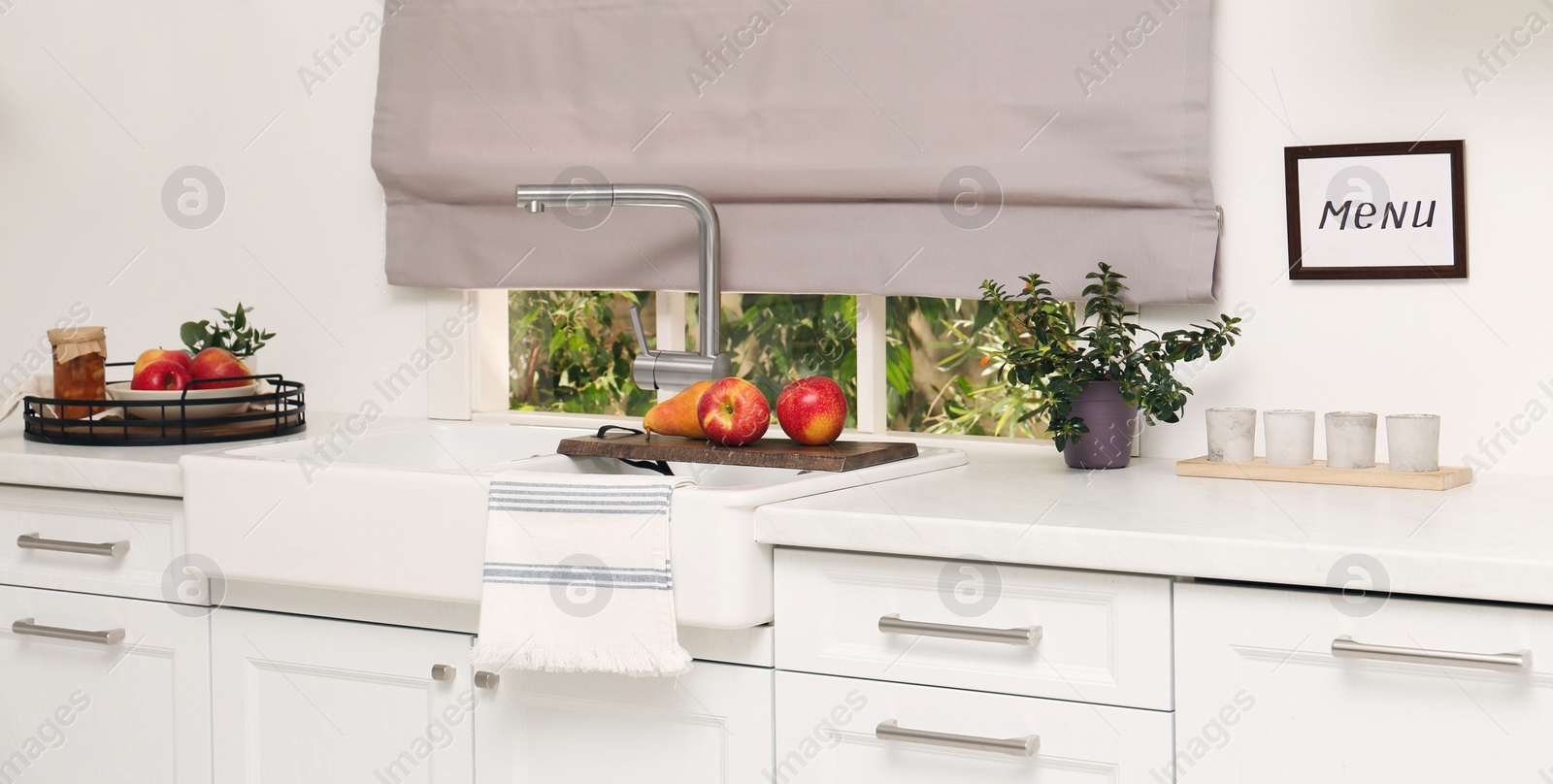 Image of White kitchen interior with double bowl sink in front of window and fresh fruits