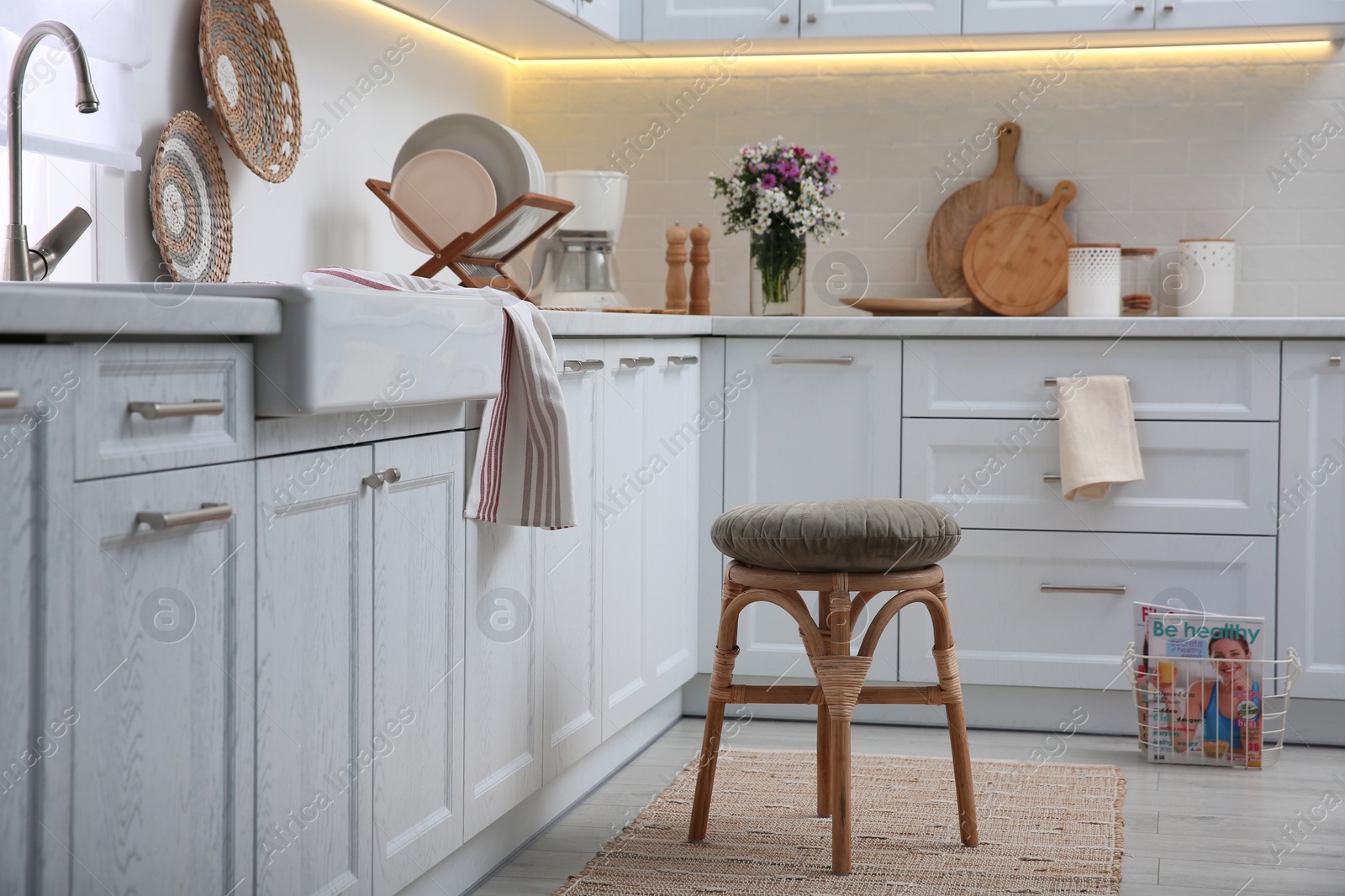 Photo of Stylish kitchen interior with wooden stool and other furniture