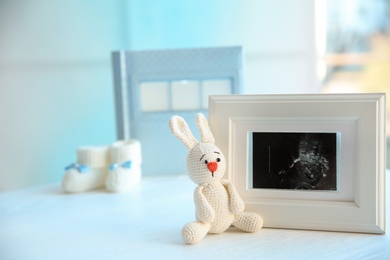 Photo of Ultrasound photo of baby and toy on table indoors, space for text