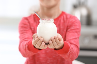 Little boy with yogurt in kitchen, closeup