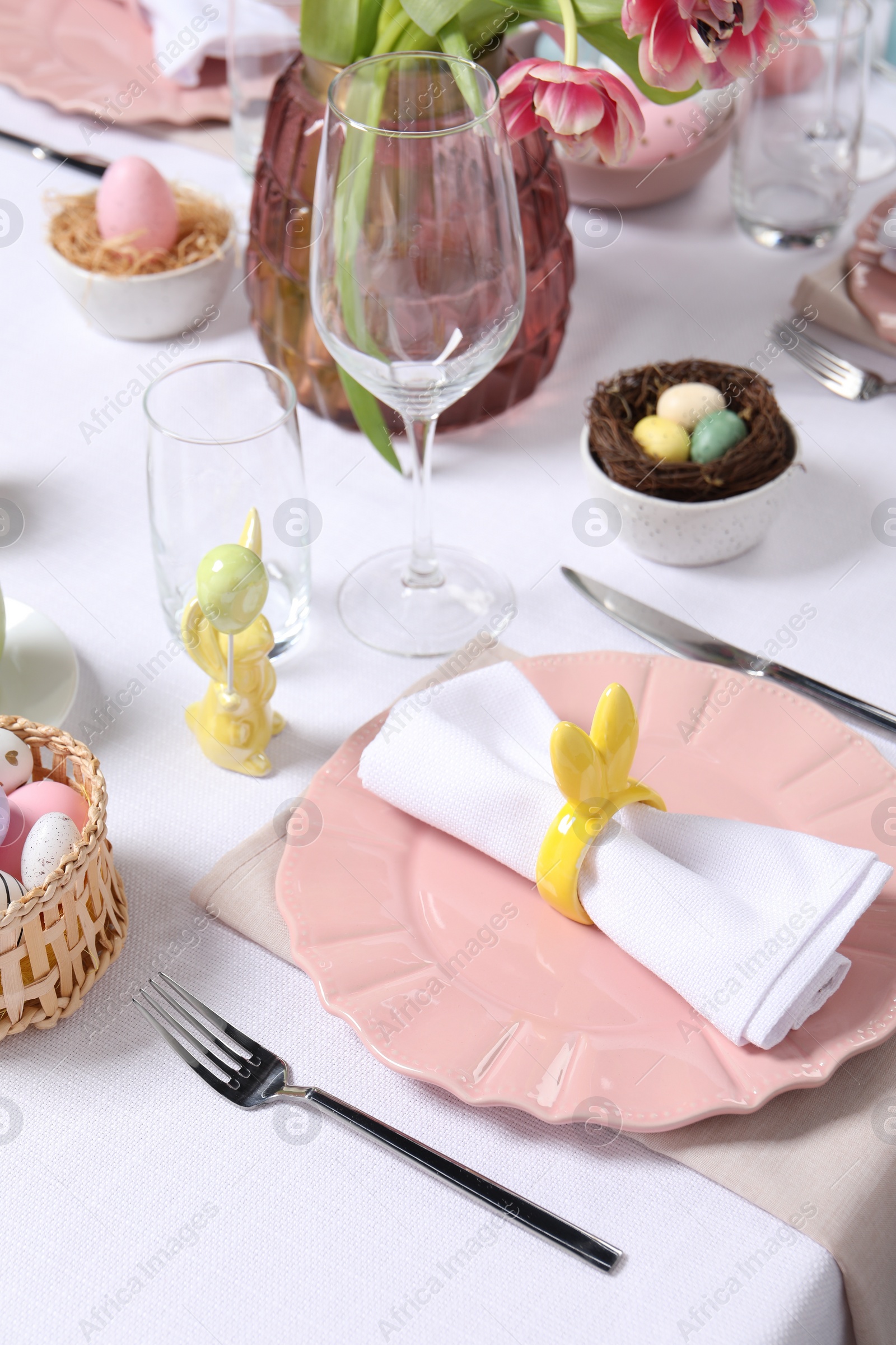 Photo of Festive table setting with napkin ring in shape of bunny ears. Easter celebration