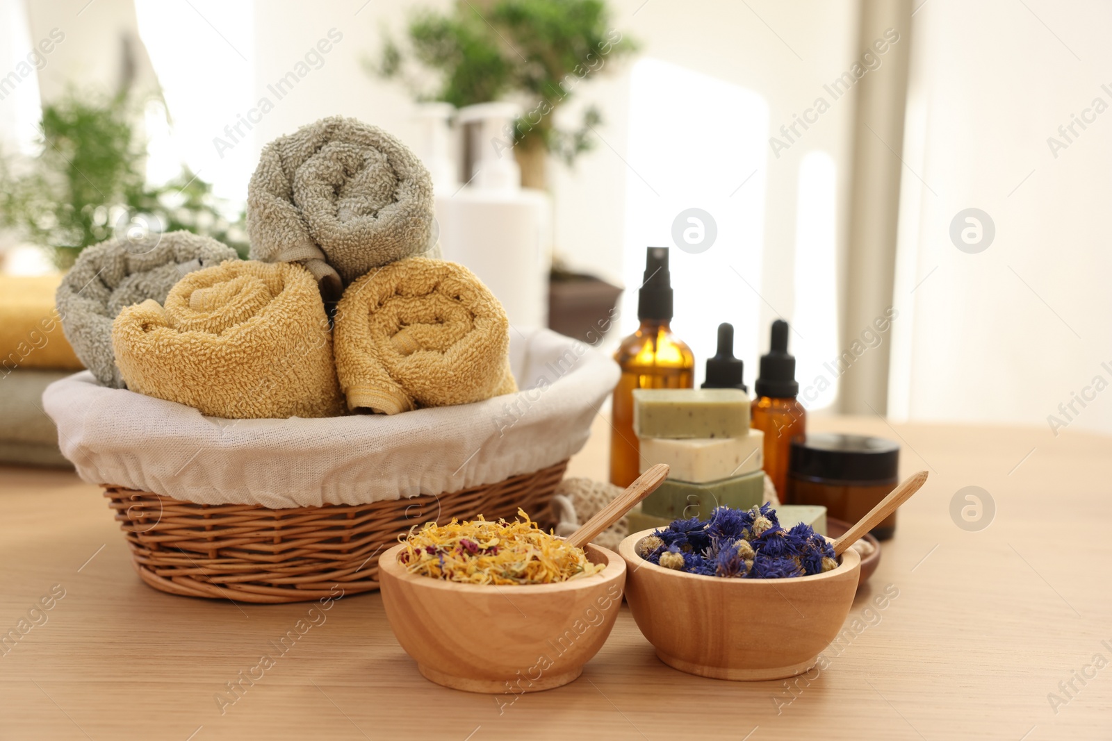 Photo of Dry flowers, soap bars, bottles of essential oils, jar with cream and towels on wooden table indoors, space for text. Spa time