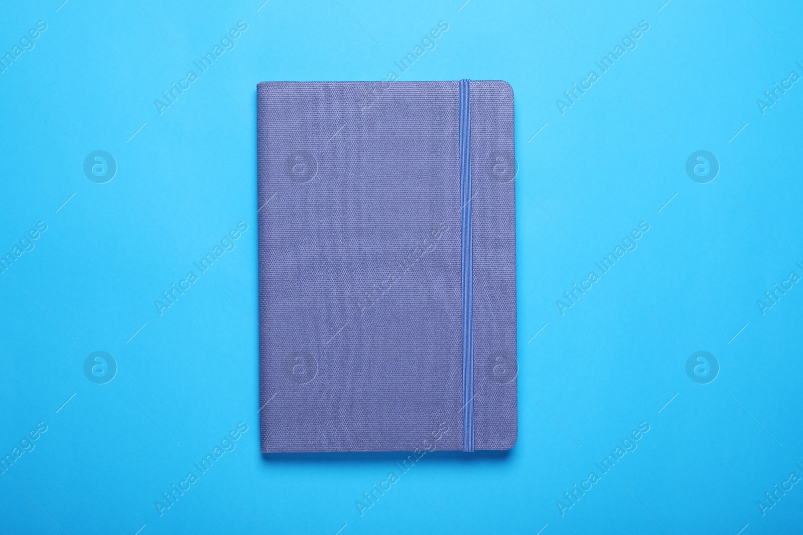 Photo of Closed notebook on light blue background, top view