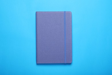 Closed notebook on light blue background, top view