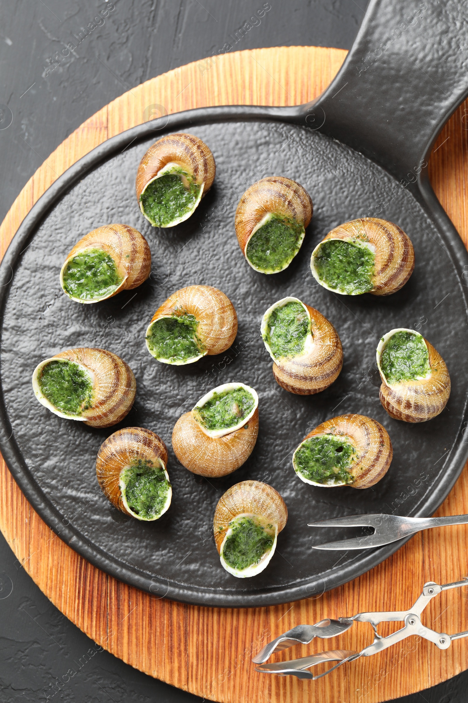 Photo of Delicious cooked snails served on grey textured table, flat lay