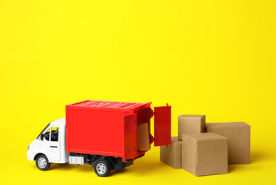Photo of Toy truck with boxes on yellow background. Logistics and wholesale concept