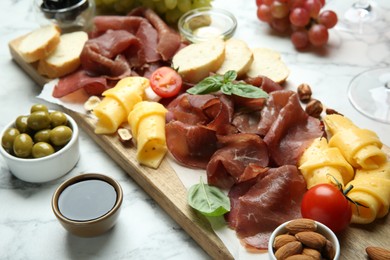 Charcuterie board. Delicious bresaola and other snacks on white marble table
