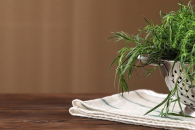 Photo of Colander with fresh tarragon leaves on wooden table, closeup. Space for text