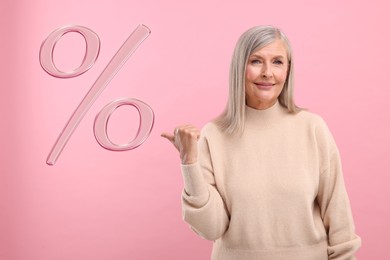 Image of Discount offer. Senior woman pointing at percent sign on pink background