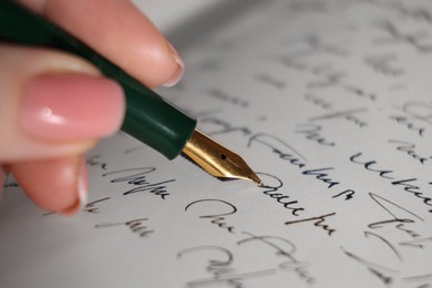 Photo of Woman writing with fountain pen in notebook, closeup