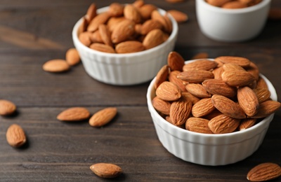 Photo of Tasty organic almond nuts in bowls on table