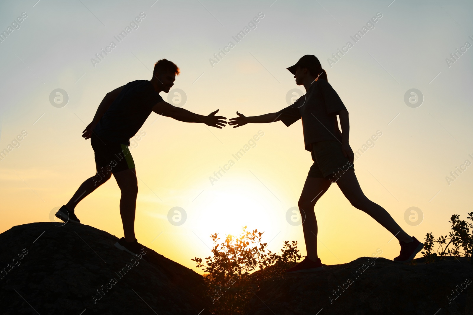 Photo of Hiker helping friend outdoors at sunset. Help and support concept