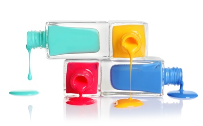 Photo of Spilled different nail polishes with bottles on white background