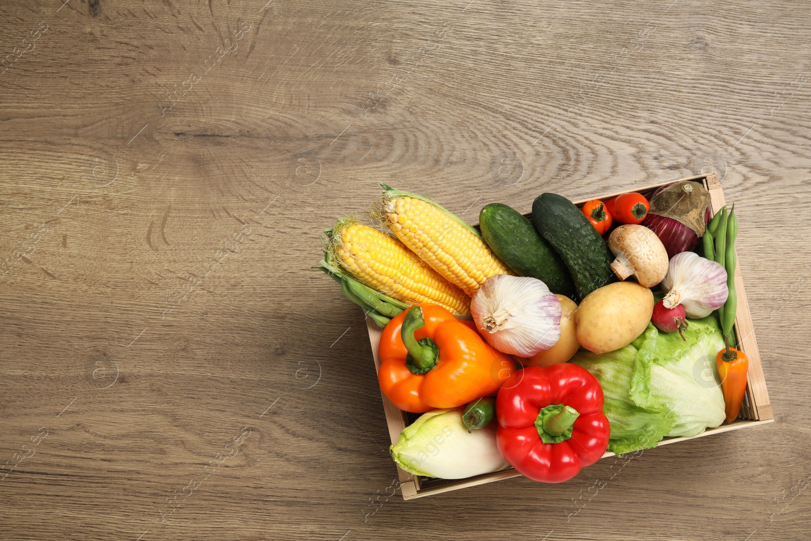 Photo of Crate with different fresh vegetables on wooden background, top view. Space for text