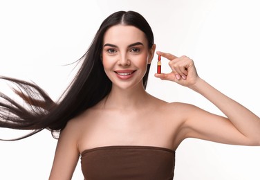 Beautiful young woman with long healthy hair holding ampoule on white background