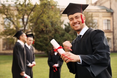 Photo of Happy student with diploma outdoors. Graduation ceremony