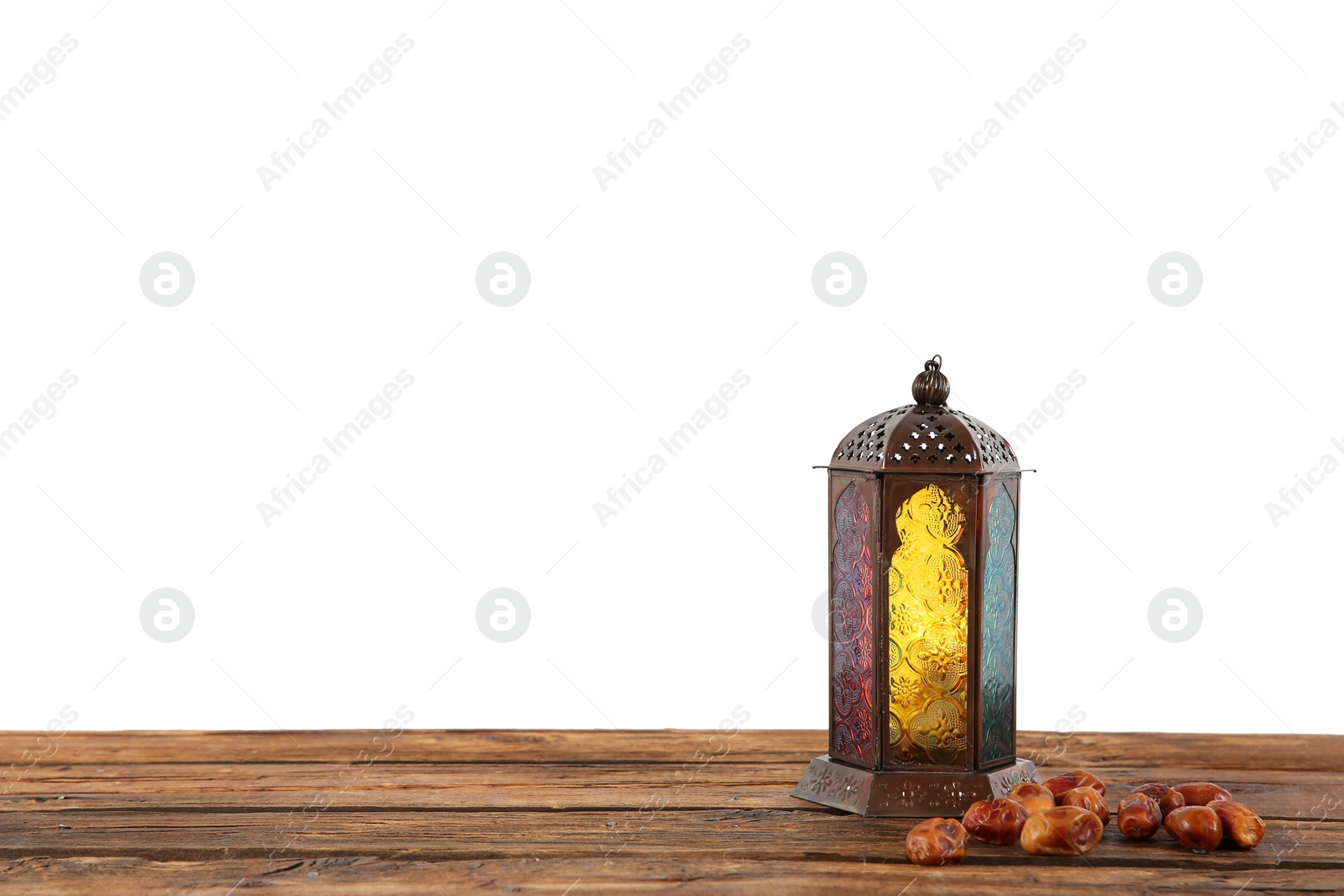 Photo of Muslim lamp and dates on wooden table against white background. Space for text