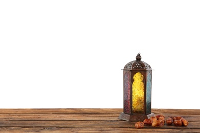 Photo of Muslim lamp and dates on wooden table against white background. Space for text