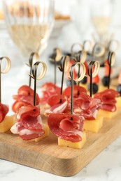 Different tasty canapes on white marble table, closeup