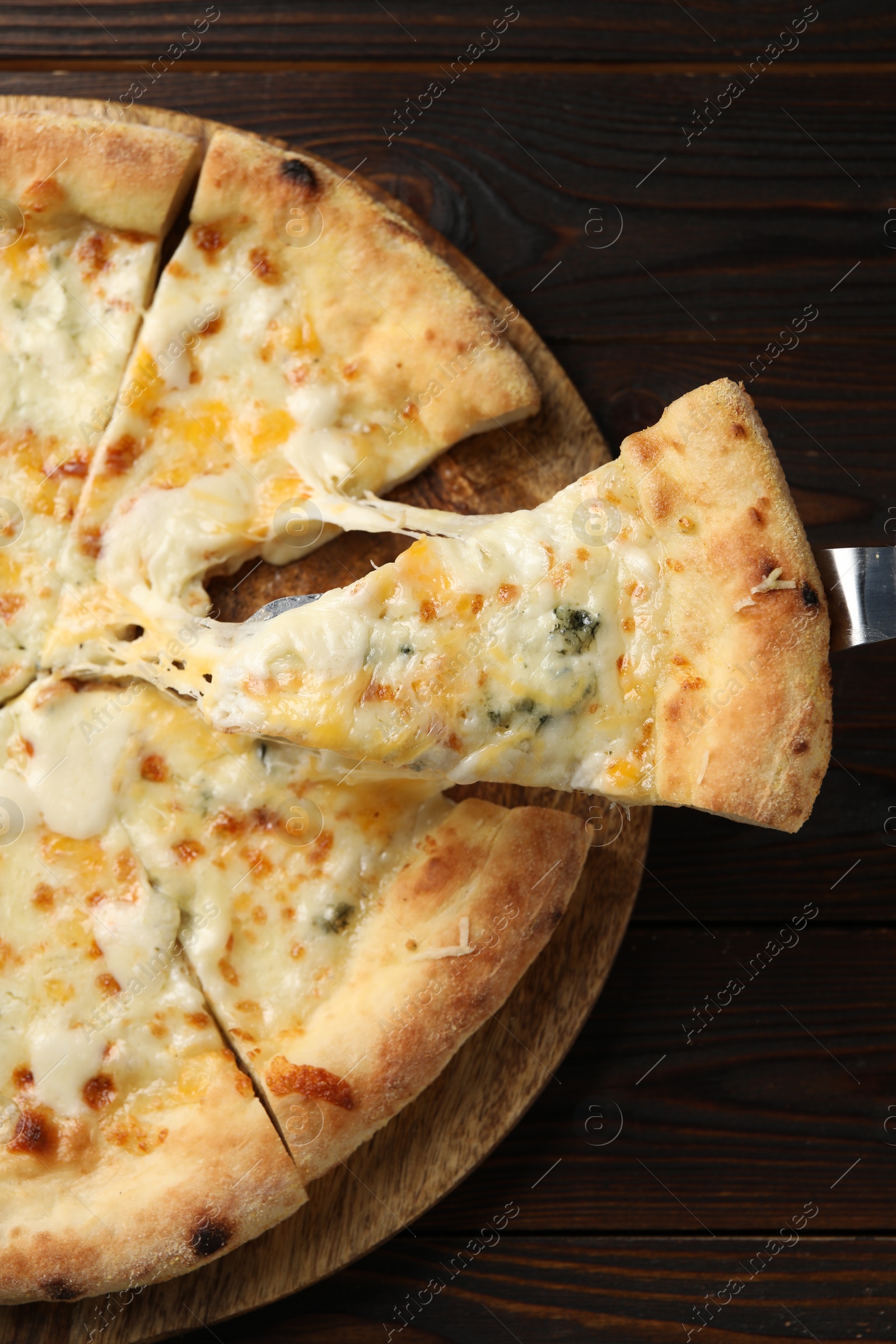 Photo of Taking piece of delicious cheese pizza at wooden table, top view