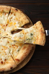 Photo of Taking piece of delicious cheese pizza at wooden table, top view