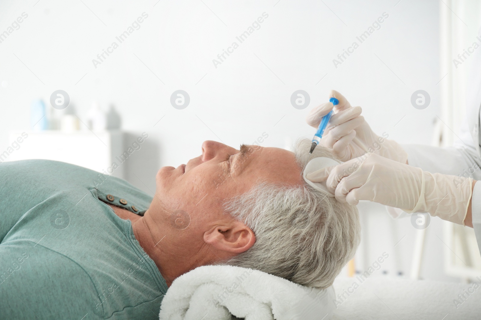 Photo of Senior man with hair loss problem receiving injection in salon