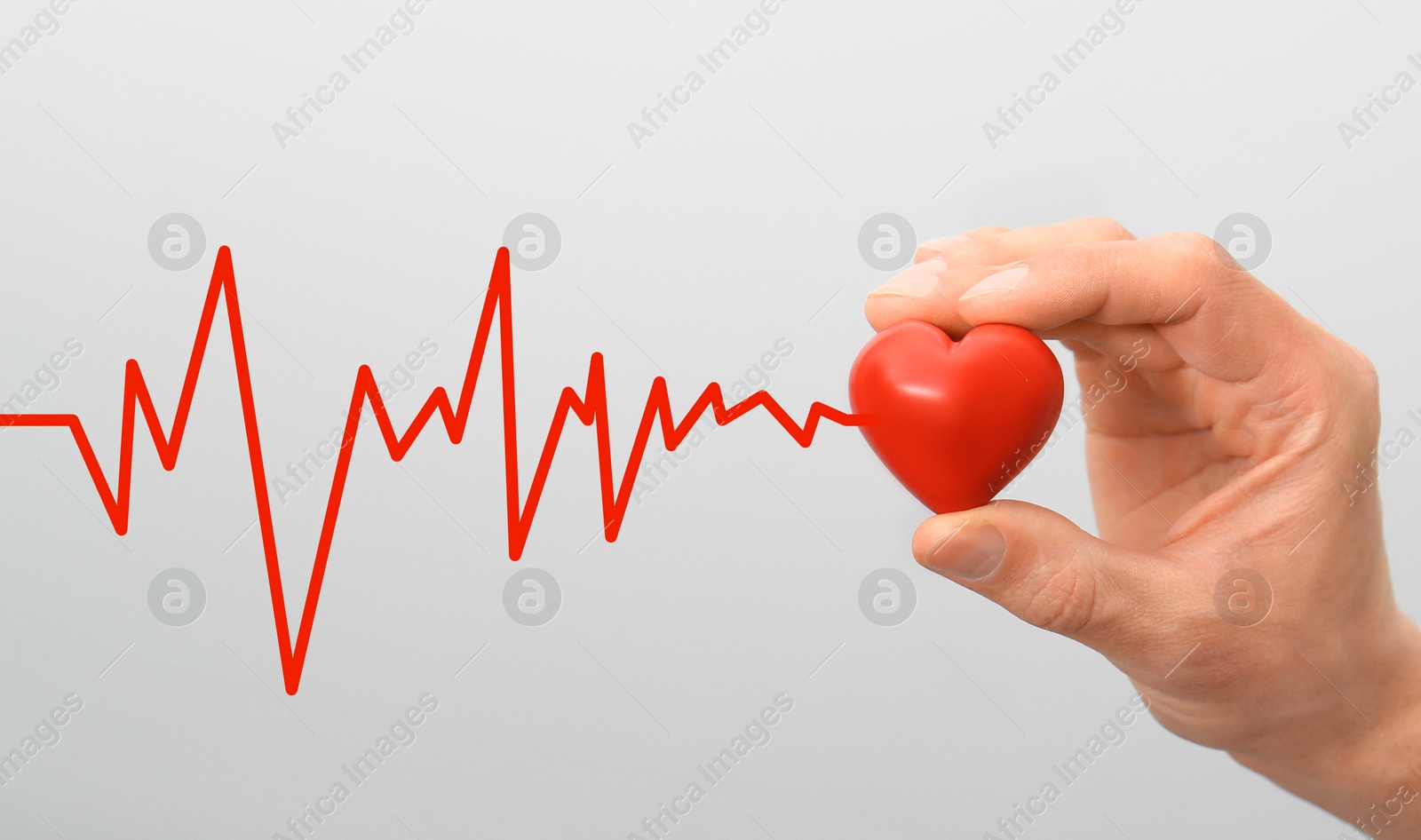 Image of Man holding small red heart on light background, closeup 