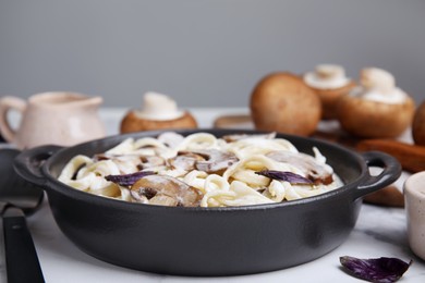 Photo of Delicious pasta with mushrooms in pan on table, closeup