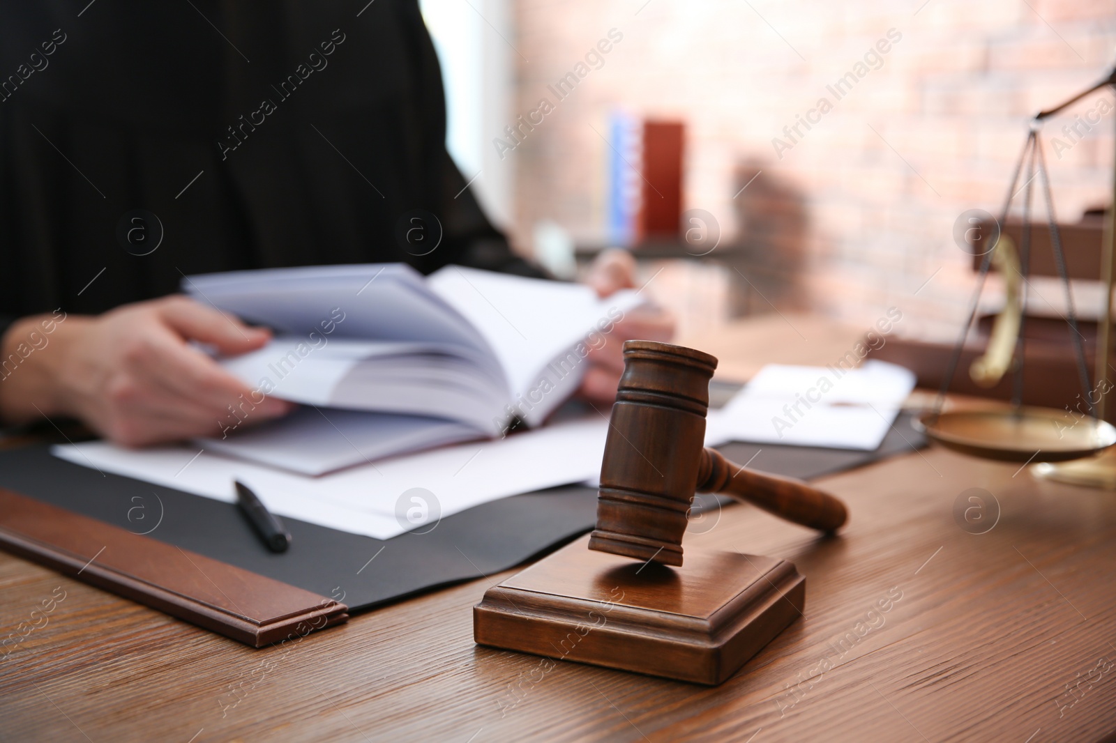 Photo of Judge working at table in office, focus on gavel. Law and justice concept