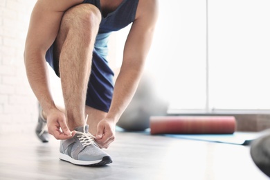 Photo of Man putting on training shoes indoors, closeup