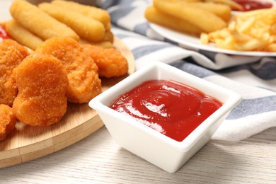 Different snacks and tasty ketchup on wooden table, closeup