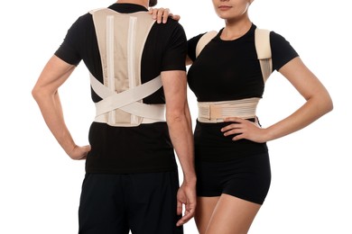 Closeup view of man and woman with orthopedic corsets on white background