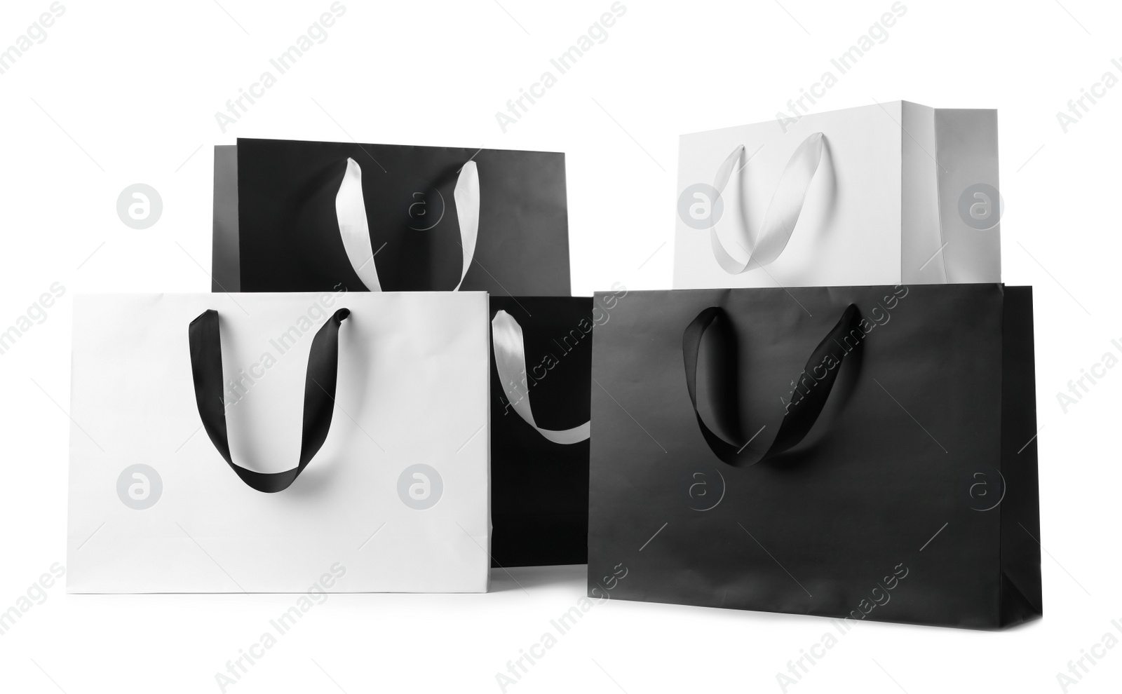 Photo of Paper shopping bags with ribbon handles on white background. Mockup for design