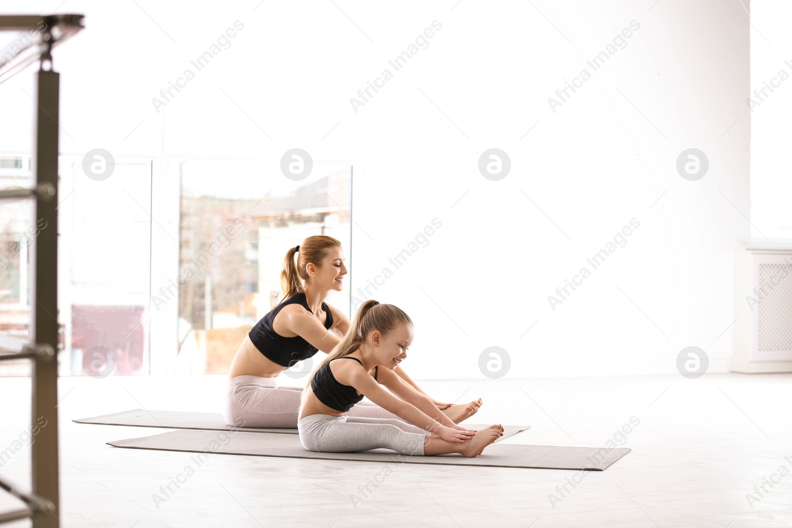 Photo of Mother and daughter in matching sportswear doing yoga together at home