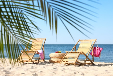 Photo of Wooden sunbeds and beach accessories on sandy shore