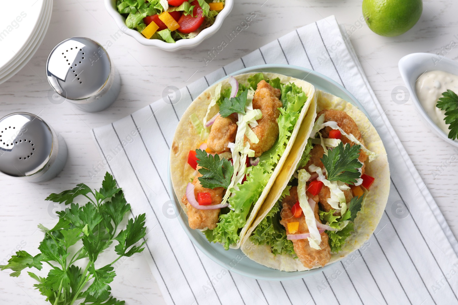 Photo of Yummy fish tacos served on white wooden table, flat lay