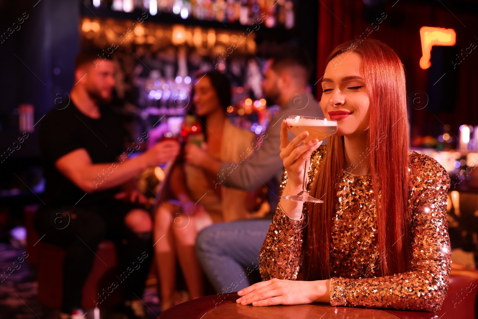 Photo of Friends spending time together in bar. Beautiful woman with fresh alcoholic cocktail at table, space for text