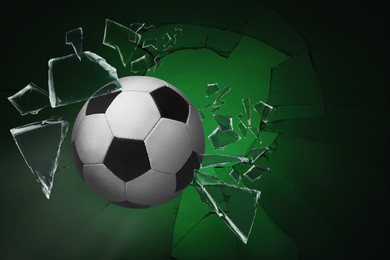 Image of Soccer ball breaking up glass against green background