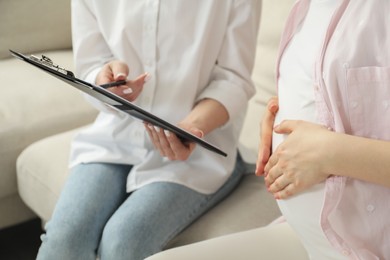 Photo of Doula working with pregnant woman at home, closeup. Preparation for child birth