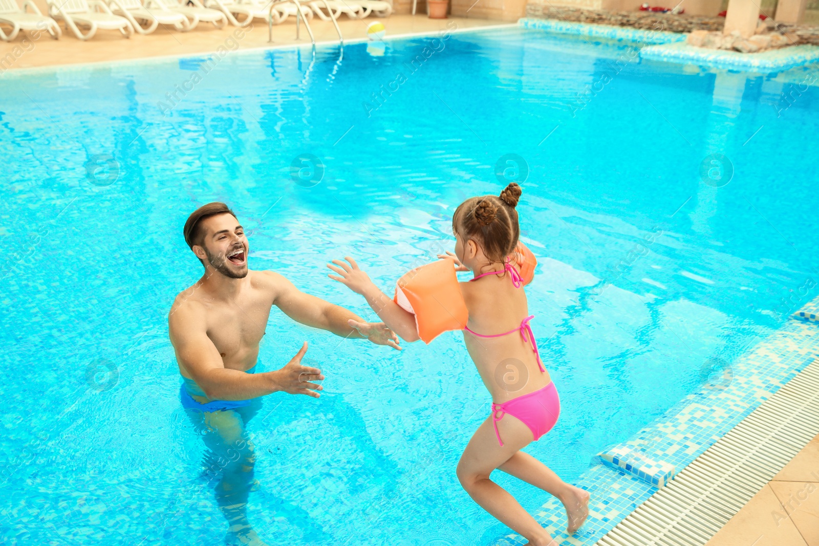 Photo of Father and daughter playing in swimming pool