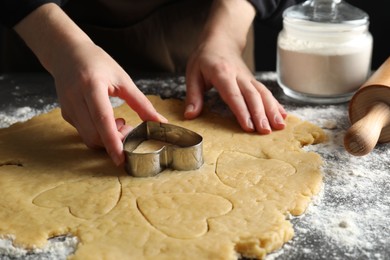 Shortcrust pastry. Woman making cookies with cutter at grey table, closeup