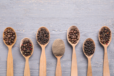 Ground pepper and corns on grey wooden table, flat lay