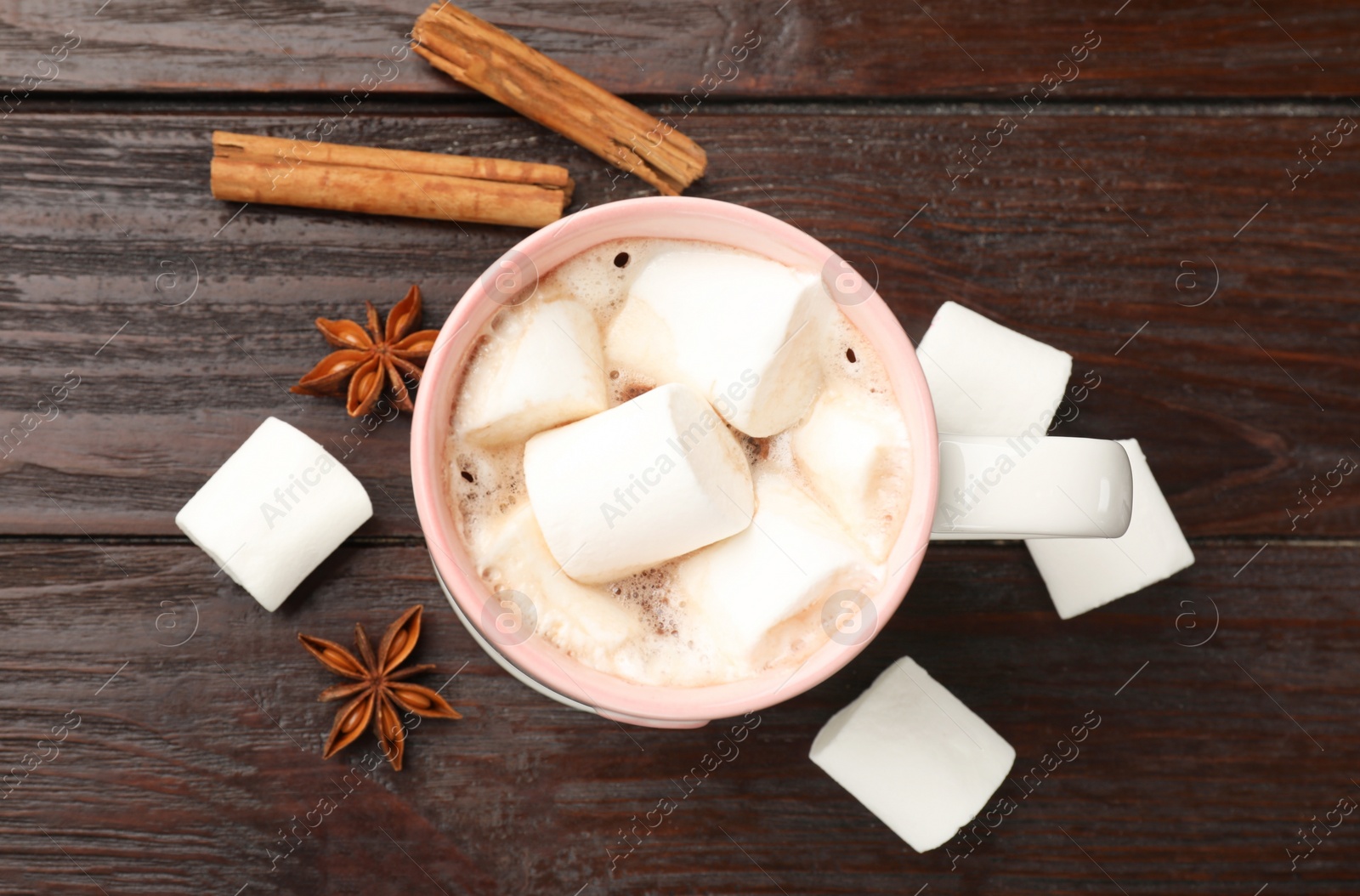 Photo of Tasty hot chocolate with marshmallows and spices on wooden table, flat lay