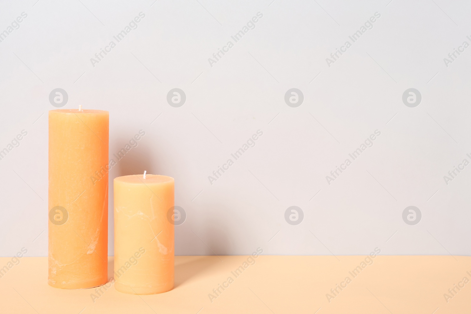 Photo of Decorative candles on table against light background