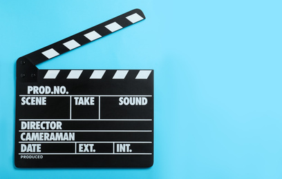 Photo of Clapper board on light blue background, top view with space for text. Cinema production