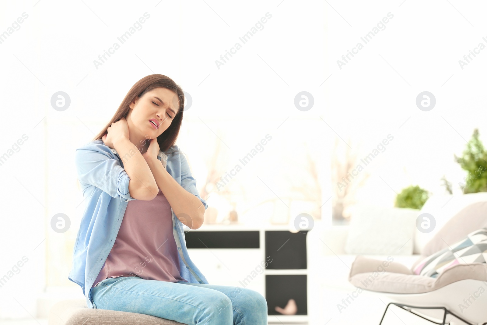 Photo of Young woman suffering from neck pain at home