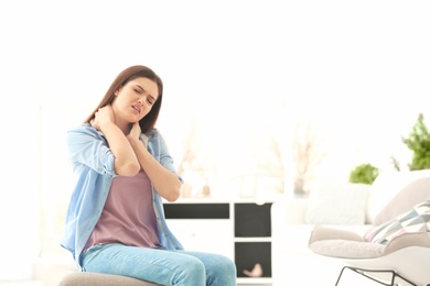 Photo of Young woman suffering from neck pain at home